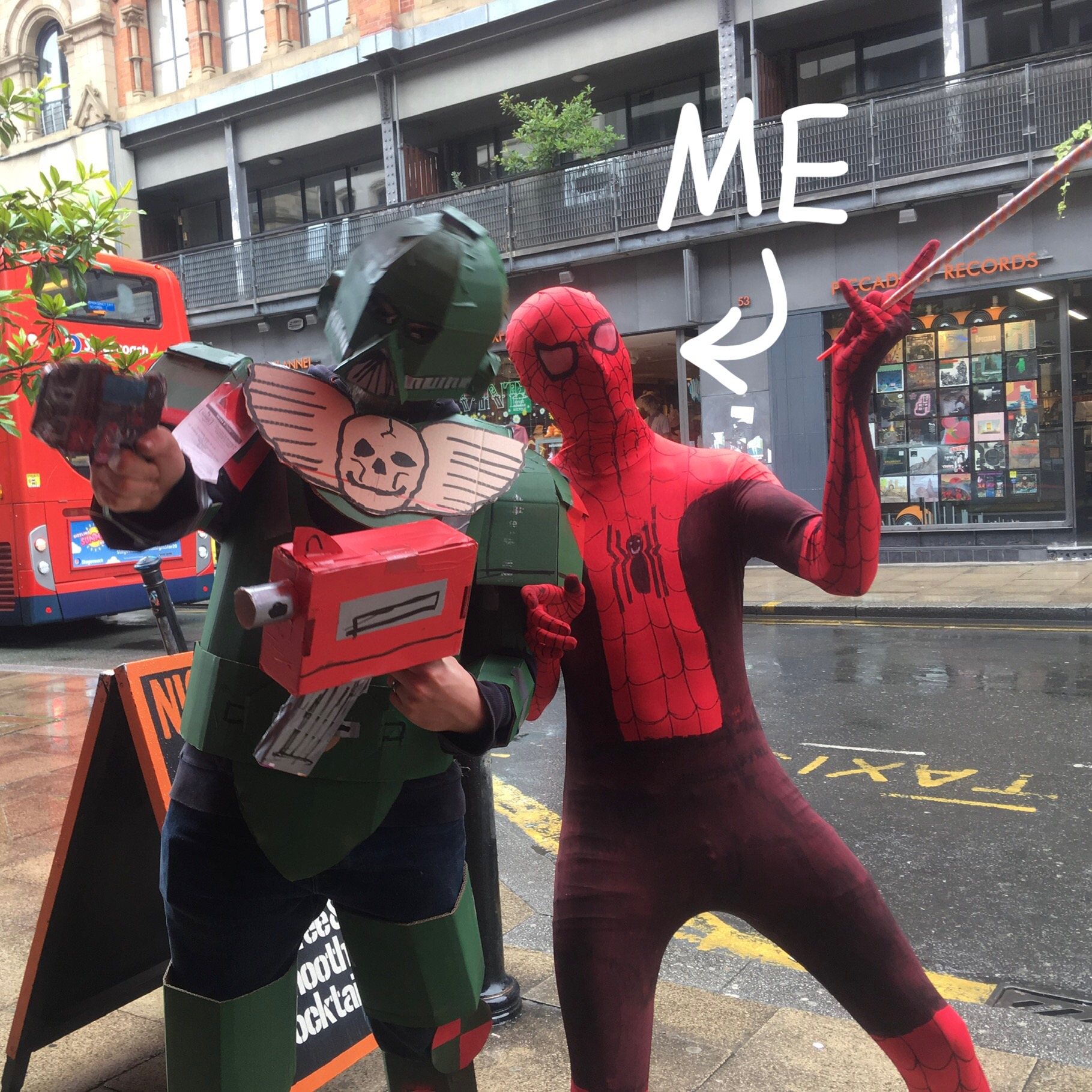 A photograph of me and a friend in homemade costumes of a space marine and spiderman, an arrow that says 'me' points to spiderman